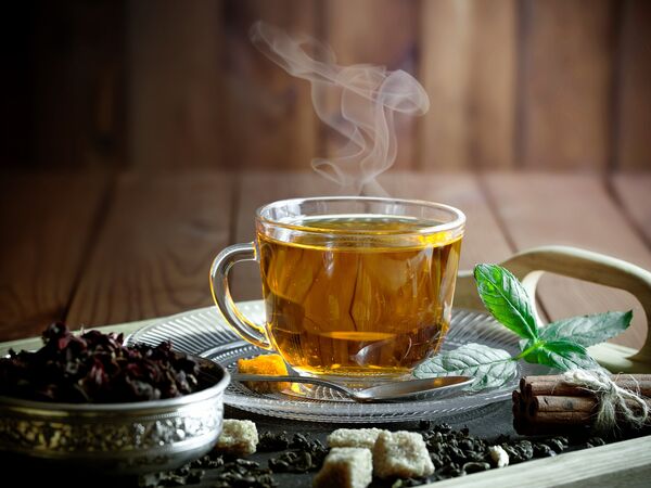 Tasse Kräutertee auf hellem Tisch mit Notizbuch